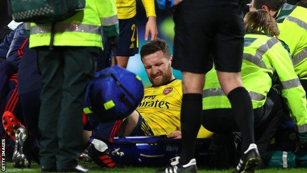 Shkodran Mustafi grimacing as he sits on a stretcher