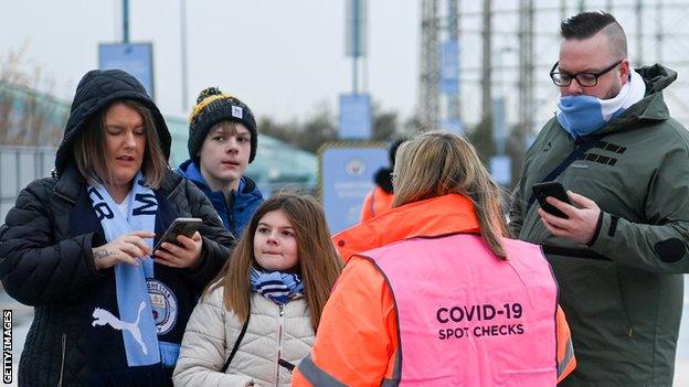 Manchester City fans show their vaccine passports before the Premier League game against Wolves on 11 December