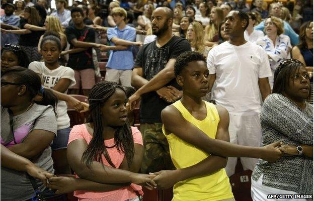 People sing "We Shall Overcome" during a vigil at TD Arena for victims of the recent church shooting in Charleston, South Carolina on June 19, 2015