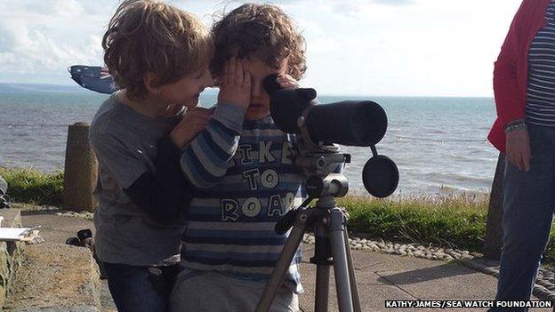 Two children look for dolphins from Castle Point in Aberystwyth