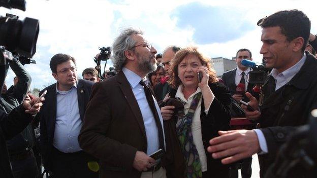 Editor-in-chief of Turkish newspaper Cumhuriyet daily Can Dundar (C) and his wife Dilk Dundar (R) look at the gunman, as they are surrounded by journalists on May 6, 2016 in Istanbul.