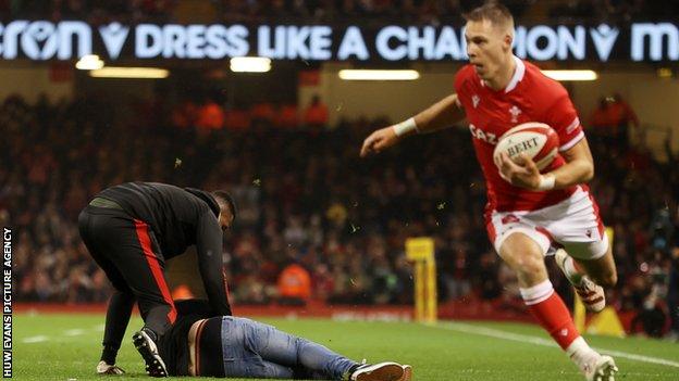 Pitch invader on ground as Liam Williams carries the ball