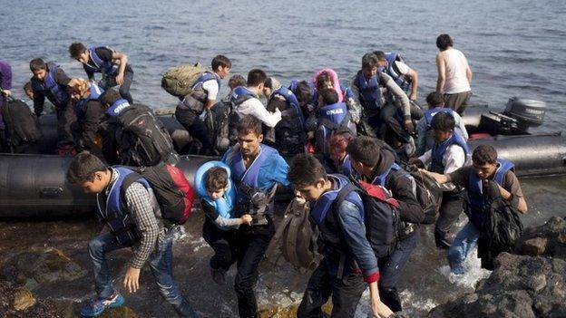 Syrian and Afghan refugees jump off dinghy as they arrive on the Greek island of Lesbos