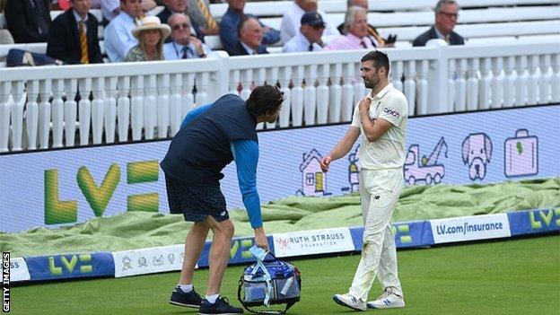 Mark Wood holds his shoulder after injuring himself