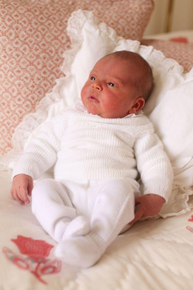 Prince Louis rests on a white pillow on a sofa.