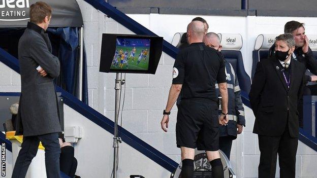 Referee Lee Mason goes to check the pitchside monitor