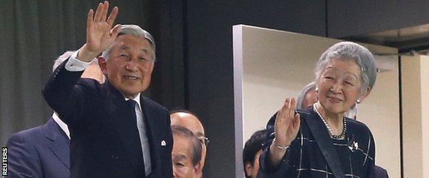 Japan's Emperor Akihito and Empress Michiko wave to the crowd after arriving at the Ajinomoto Stadium