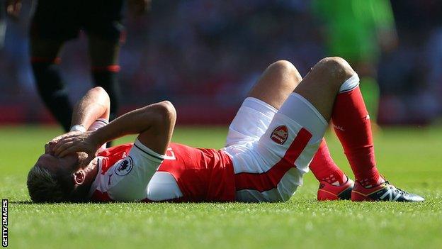 Aaron Ramsey holds his head after injuring a hamstring playing for Arsenal against Liverpool