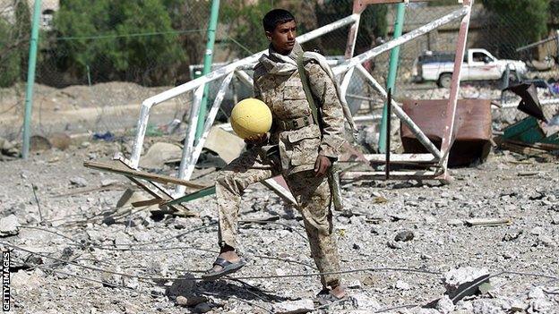 An armed Shiite Huthi rebel holds a ball at the compound of Sanaa's al-Yarmuk football club, which was reported hit by an air strike by the Saudi-led coalition the previous day in 2015 in the Yemeni capital's northern al-Rawda district.