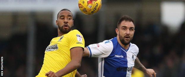 AFC Wimbledon's Tyrone Barnett is challenged by Peter Hartley while with Bristol Rovers