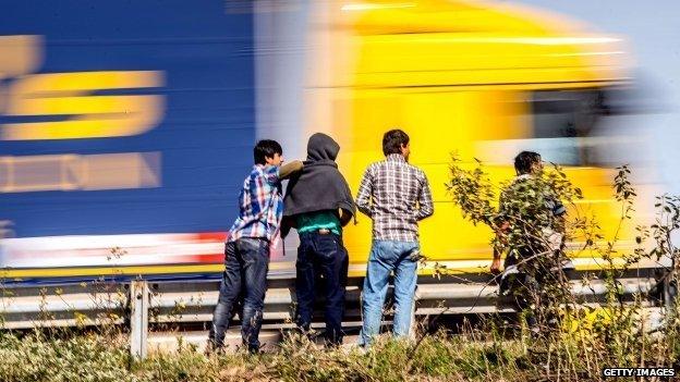 A truck passes as migrants stand beside the road in Calais