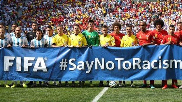 Argentina and Belgium players and referees pose with a banner before a World Cup game in 2014