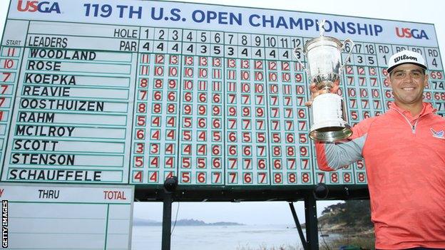 Gary Woodland with the US Open trophy in front of the leaderboard