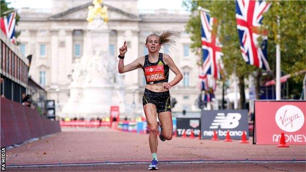 Charlotte Purdue crosses the finish line of the London Marathon with Buckingham Palace in the background