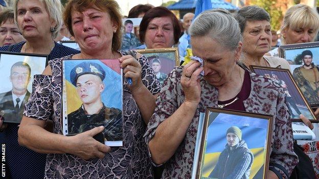 Ukrainian mothers and widows cry as they hold pictures during a memorial rally