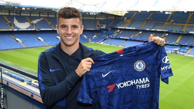 Mason Mount holding up a Chelsea shirt