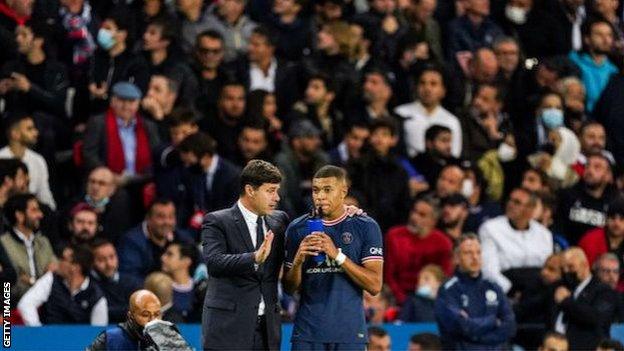 Mauricio Pochettino talks to Kylian Mbappe in front of PSG fans