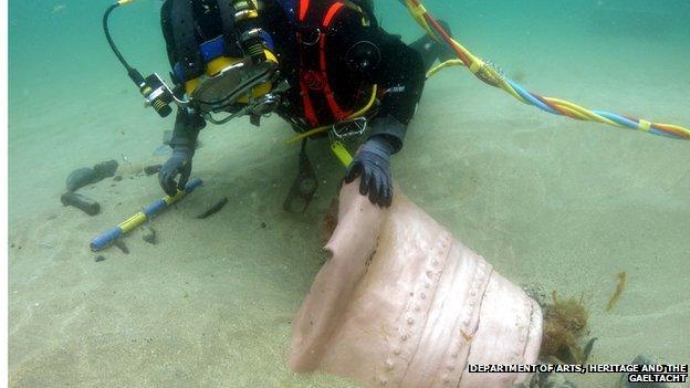 A diver bringing a cauldron up from the sea bed