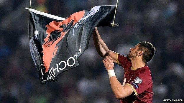 Serbia's Stefan Mitrovic grabs a flag with Albanian national