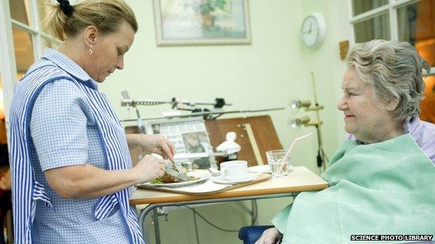 Care home worker feeding a resident