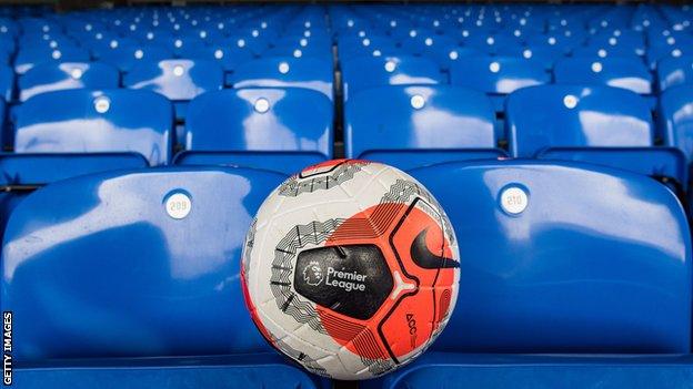 A Premier League match ball rests on a row of empty seats in a stand at a Premier League stadium