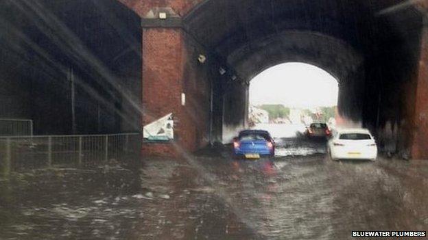 Cars driving through flood water in Manchester. the water is close to the top of the wheels