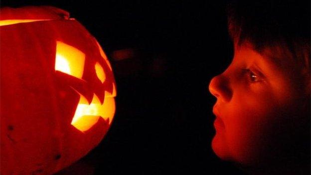 Child looking at a Halloween Pumpkin