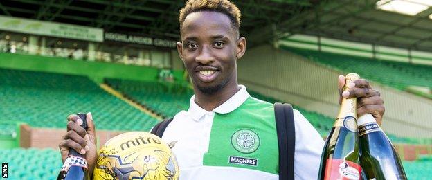 Moussa Dembele celebrates with the match ball and sponsors' bottles of champagne