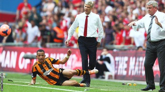 Liam Rosenior of Hull City slides for the ball as Arsene Wenger manager of Arsenal and Steve Bruce, manager of Hull City look on during the FA Cup final