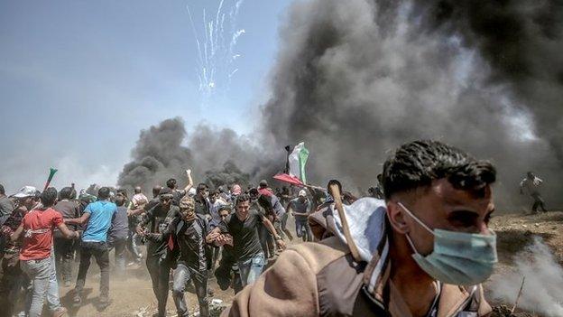 Palestinian protesters run for cover from Israeli tear-gas during clashes after protests near the border with Israel in the east of Gaza Strip,