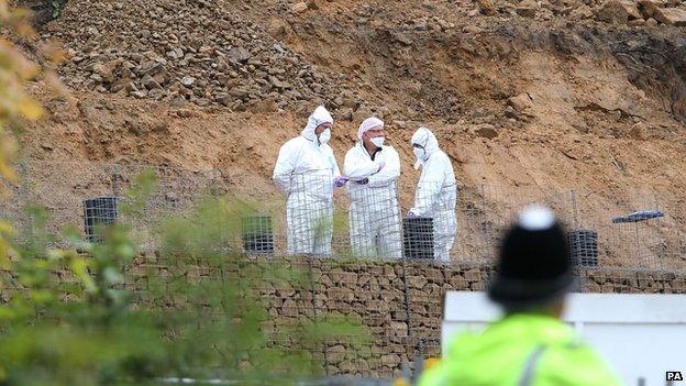 Forensic scientists in white overalls analysing site