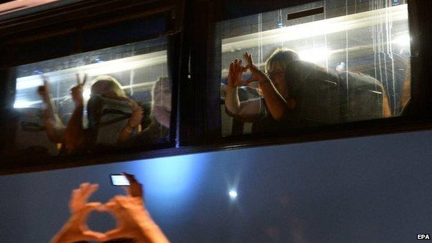 Tourists gesture peace signs from inside a bus as demonstrators take part in a rally in front of the Hotel Imperial Marhaba in Sousse