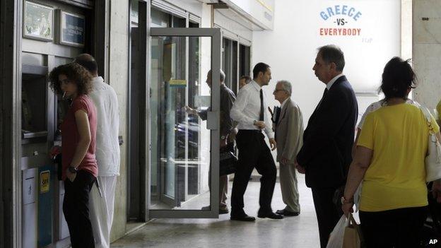 People use the ATMs of a bank as others exit from the branch in Athens