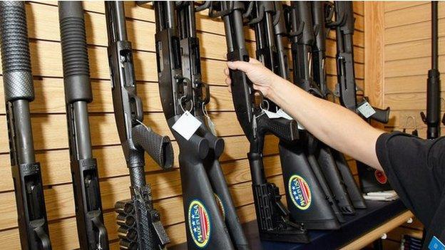 A man takes a gun from a display of shotguns at The Gun Store in Las Vegas