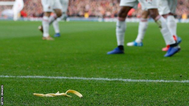 Pierre-Emerick Aubameyang celebrates scoring a goal with a banana skin on the pitch in front of him
