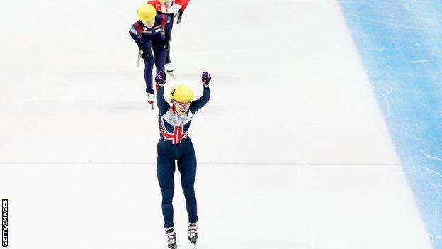 Elise Christie raises her arms aloft after winning the 1000m in Dordrecht