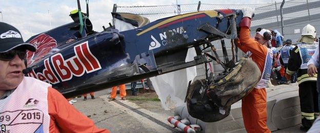 Course marshals remove the crashed car of Toro Rosso driver Carlos Sainz