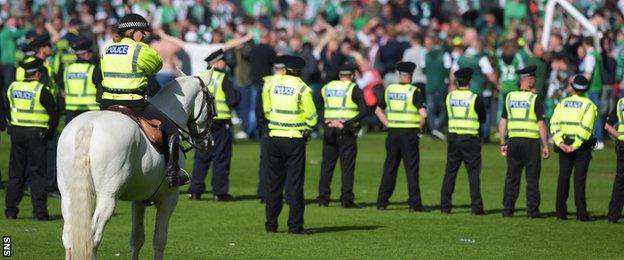 A police cordon helps to get fans off the Hampden pitch