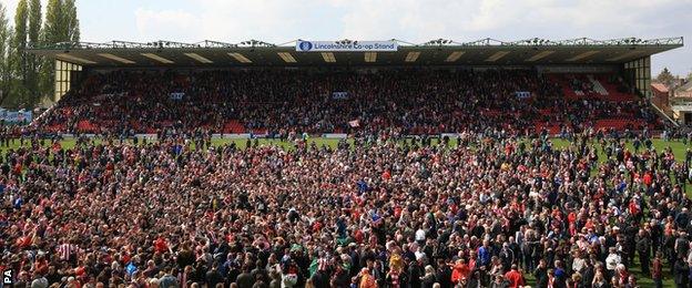 Lincoln City supporters invade the pitch after