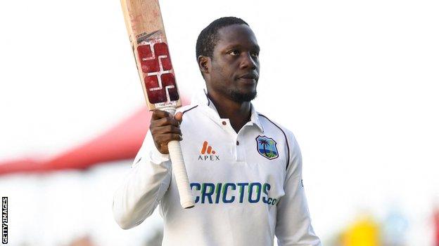 West Indies batter Nkrumah Bonner raises his bat to the crowd after hitting a century against England