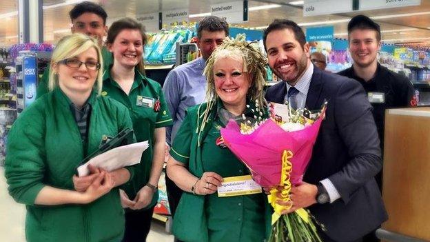 Store manager Simon Nellis presents flowers to cashier Lin