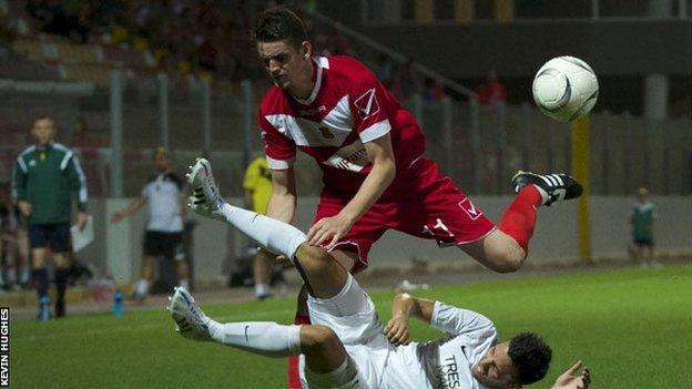 Newtown's Jason Oswell (in red) battles for the ball in Valletta