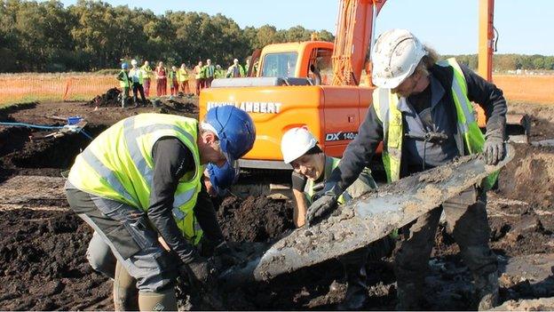 Archaeologists at the dig holding the propeller