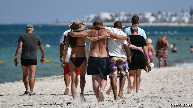 Holidaymakers walk along the beach in Sousse