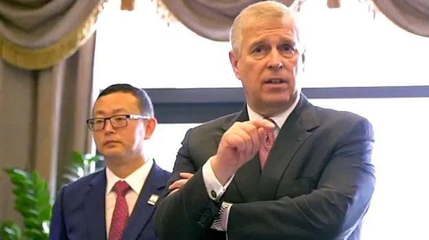 Prince Andrew stands in front of Yang Tengbo, who has short black hair and wears glasses and a blue jacket.