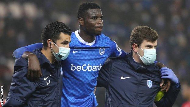 Nigeria striker Paul Onuachu (centre) led off the pitch by Genk's medical team