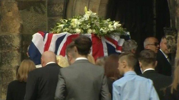 Bruce Wilkinson's coffin being carried into a church followed by mourners