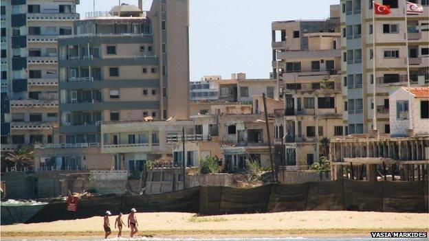 People walking on the beach with Varosha in the background