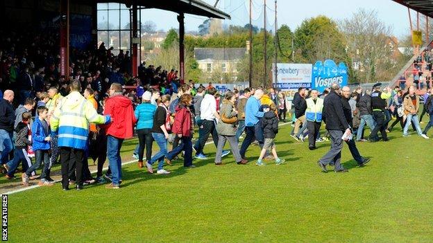 Fans in the Stagecoach Stand are evacuated onto the pitch