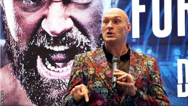 Tyson Fury speaks on the mic at a news conference